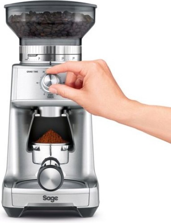 Zilverkleurige Sage koffiemolen, met een hand die de draaiknop voor maaltijd instelt.