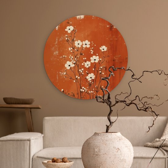 Cercle mural rond avec des fleurs blanches sur fond rouille, au-dessus d'un canapé.