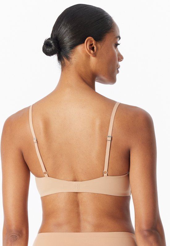 Achterkant van een model dat een beige, naadloze beugel-vrije bh draagt. De bandjes zijn verstelbaar.
