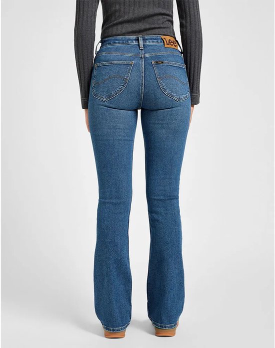 Achterzicht van een vrouw in een blauwe Lee-spijkerbroek met laarsuitloop en een bruine Lee-patch.