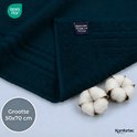 Donkerblauwe badmat, gevouwen, met OEKO-TEX label en twee katoenbollen ernaast. Formaat 50x70 cm.