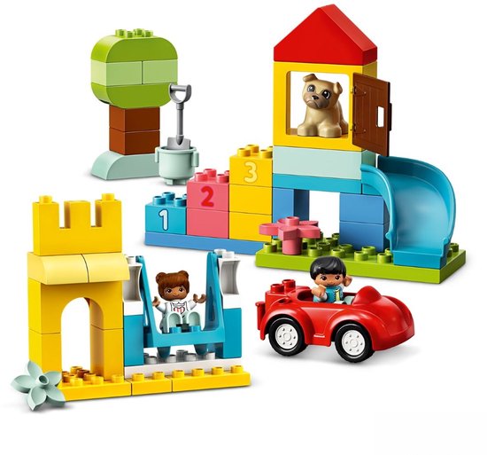 Jouet avec un château jaune, glissière bleue, maisonnette avec chien, arbre avec figurine et voiture.