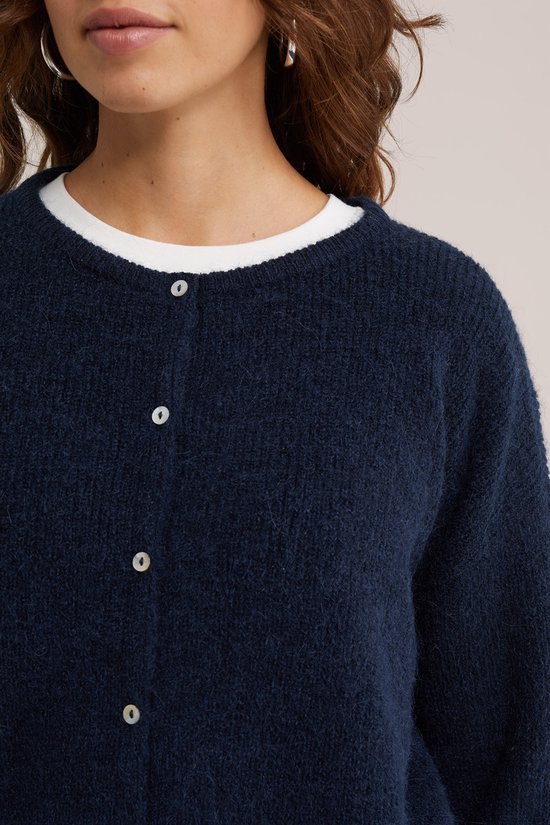 Close-up van donkerblauw gebreid vest met witte top