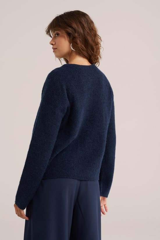 Model draagt donkerblauw gebreid vest van achteren