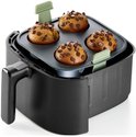 Grijze siliconen bakvorm met 4 ronde uitsparingen, gevuld met vier chocolademuffins, geplaatst in een zwarte heteluchtfriteuse.