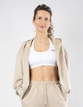 Model in beige hoodie met rits, witte sportbeha en beige joggingbroek met tekstopdruk.