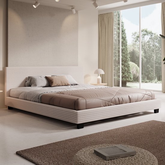 Lit double beige à côtes prononcées, avec une couette et des oreillers marron et gris clair.