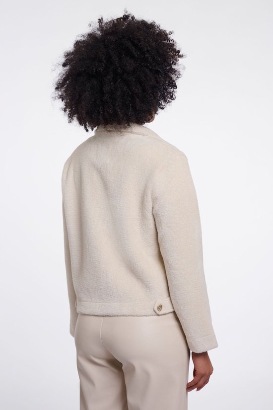 Vue arrière d'un mannequin portant une veste en tricot blanc cassé avec un bouton doré au dos.