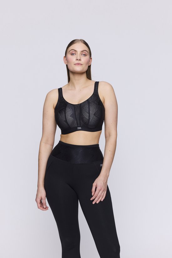 Model in een zwarte sportbeha met geometrische print en zwarte legging.