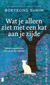 Boekomslag met een witte kat die onder een boom in een veld met paarse bloemen zit. Titel: Wat je alleen ziet met een kat aan je zijde.