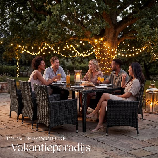 Een groep van vijf vrienden geniet van een etentje aan een zwarte wicker tuinset onder een boom met kerstverlichting.