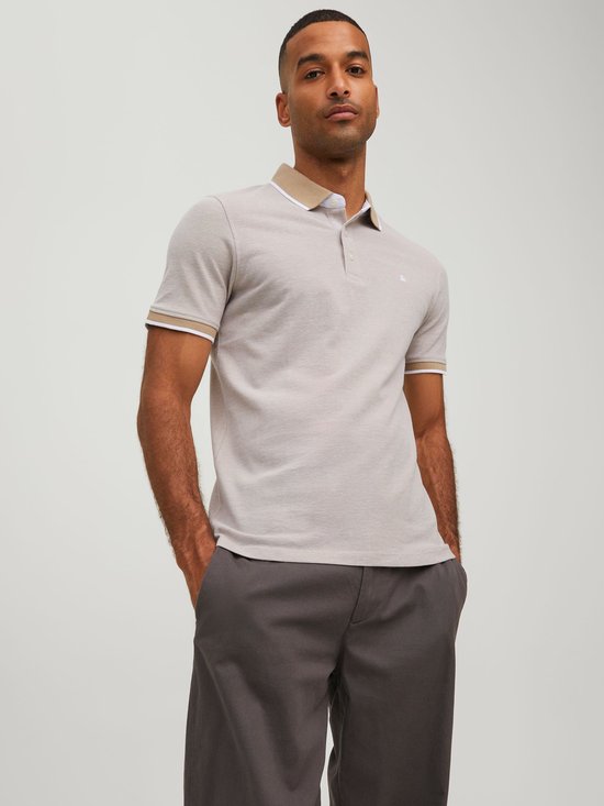 Man draagt beige polo met beige en witte boorden aan de mouwen en kraag.