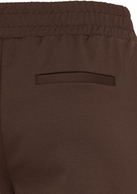Close-up van de achterkant van een bruine wijde broek met elastische tailleband en een achterzak.