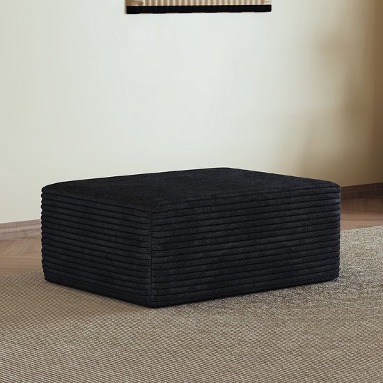 Zwarte hocker met ribstof en gedetailleerde naden, op een gebreid tapijt.