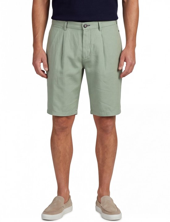 Man met korte, lichtgroene broek met plooien en een donkerblauw shirt.