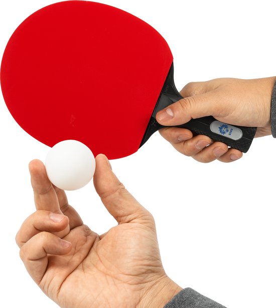 Hand houdt een witte tafeltennisbal vast bij een rood tafeltennisbatje.