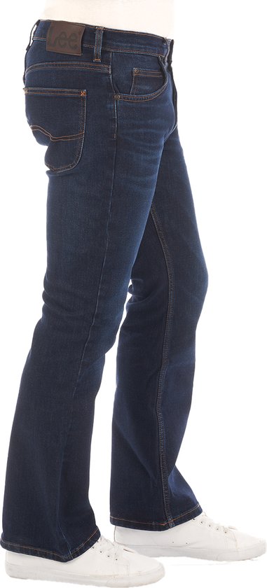 Man in donkerblauwe bootcut jeans van Lee, gezien vanaf de zijkant.