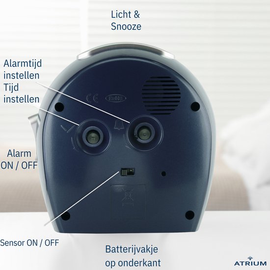 Achterkant van de donkerblauwe wekker. Knoppen voor alarm en tijd instellen, batterijvakje.
