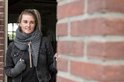 Model met gebreide grijze sjaal en vingerloze handschoenen. Draagt een zwarte spijkerjas.