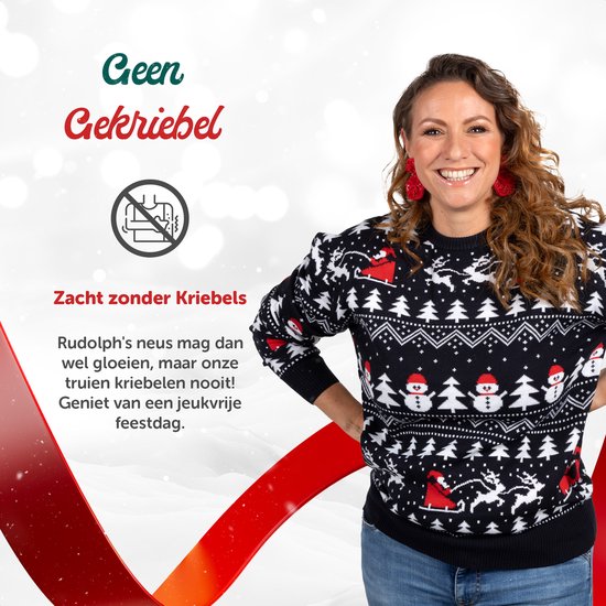 Vrouw draagt marineblauwe kersttrui met sneeuwpoppen en rendierpatronen, staat op een witte achtergrond.