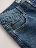 Gedetailleerde close-up van de denim stof met zichtbare naden en koperen knopen.