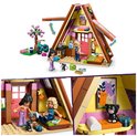 Lego Friends speelgoedhuisje met roze accenten, fiets en poppetjes. Close-up van het interieur met twee poppetjes en een kat op een schilderij.