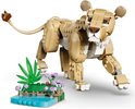 LEGO leeuwin model in beige en bruine stenen, staand bij een blauw waterpartij met groene planten en paarse bloemen.