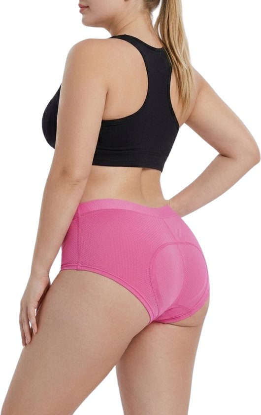 Femme à vélo portant un short de cyclisme rose avec rembourrage antichoc, vue de côté.