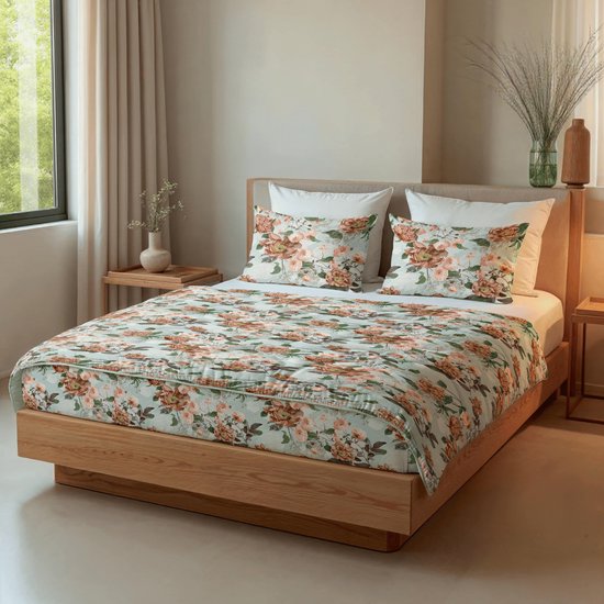 Een tweepersoonsbed met lichtgroen bloemenprint dekbed en bijpassende kussens. De houten ombouw van het bed is zichtbaar.