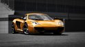 Oranje McLaren MP4-12C met zwarte velgen op een circuit.