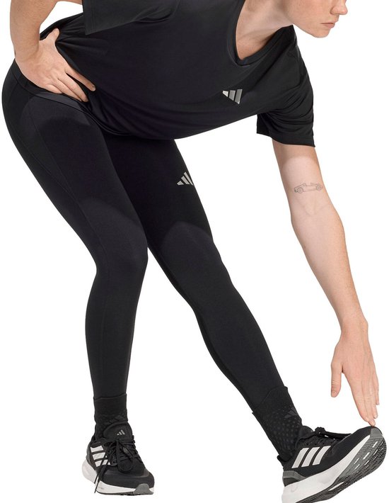 Model in zwarte Adidas legging met drievoudige streep logo op linker heup.