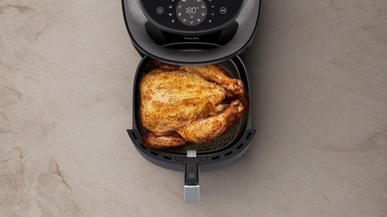 Zwarte Philips Airfryer met een hele goudbruine kip in de mand.