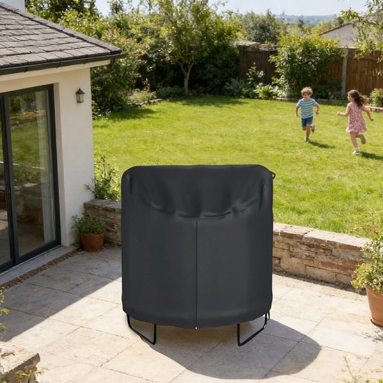 Zwarte trampolinehoes met rits op een betegeld terras, met kinderen die spelen op de achtergrond.
