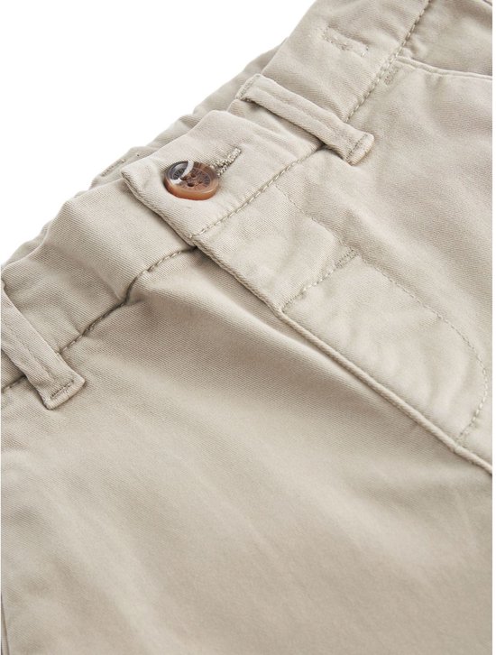 Detail van de knoopsluiting en tailleband van een beige kinderbroek.