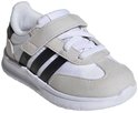 Witte kindersneaker met lichte grijze suède accenten, zwarte Adidas-strepen en klittenbandsluiting, van voren gezien.