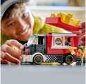 Kind bouwt LEGO City snackbartruck. Rode truck met frietjes en twee poppetjes bij de serveeropening.
