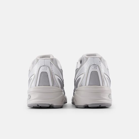 Achterkant van twee lichtgrijze New Balance 740 sneakers met metallic zilveren accenten.