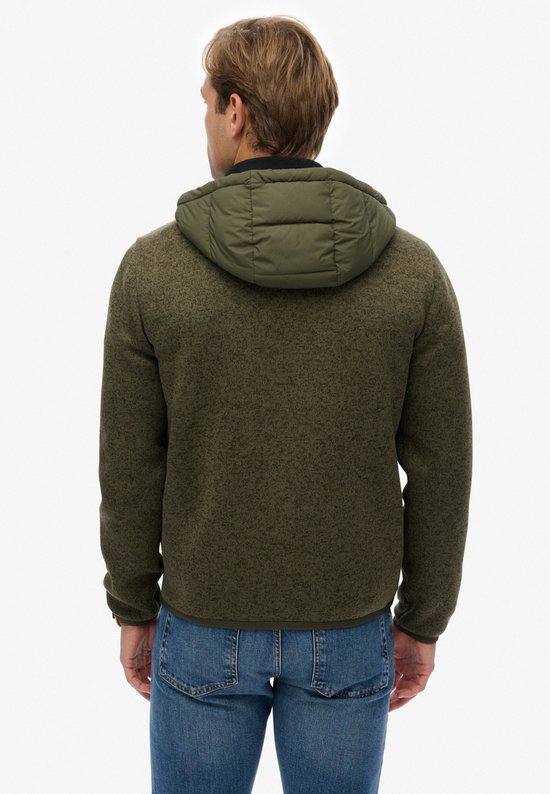 Achterkant van een man in olijfgroene jas met capuchon, gewatteerd rugpand en gebreide mouwen.