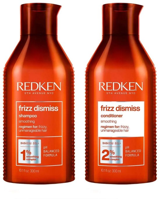Twee flessen Redken Frizz Dismiss shampoo en conditioner. Oranje flessen met witte en rode tekst. 10.1 fl oz 300 ml.