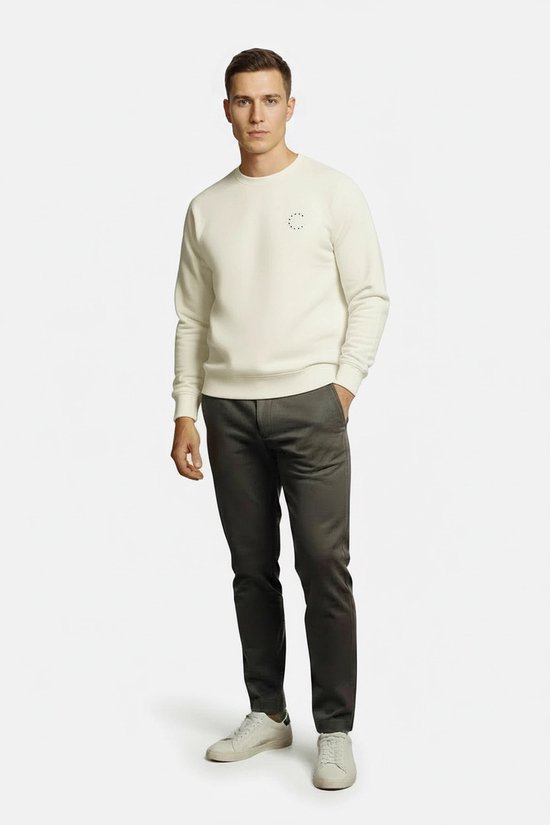 Man met off-white oversized sweater, donkergrijze broek en witte sneakers.
