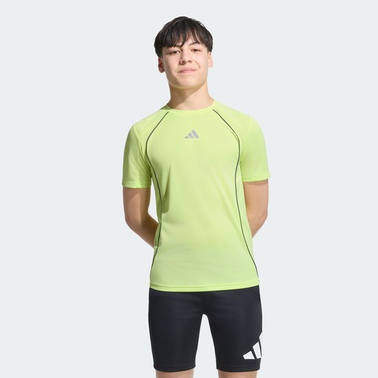 Jongen in geel T-shirt met korte mouwen en donkere biezen, met het Adidas logo op de borst.