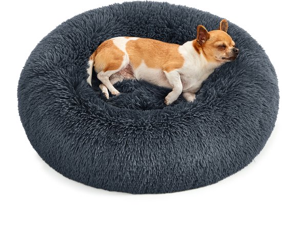 Een chihuahua slaapt in een rond, donkergrijs, pluizig hondenbed.