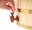 Hand die de houten tapkraan van een grenenhouten vat opent.