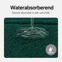 Water wordt op de donkergroene badmat gegoten en absorbeert onmiddellijk.