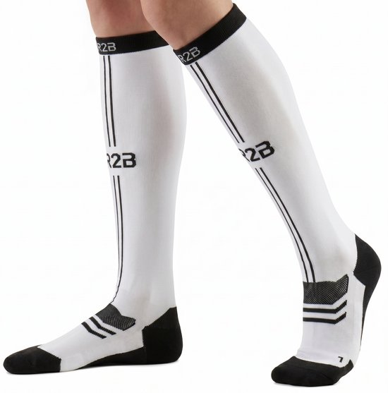 Voeten van een persoon met witte compressiekousen met zwarte accenten en logo.