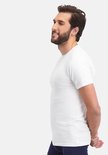 Man met baard, zijkant van een wit T-shirt met ronde hals, handen achter de rug.