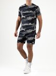 Man in een grijs en zwart camouflage sportshirt en short, met witte sportsokken en schoenen.