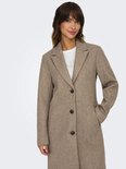 Vrouw in bruine jas met knopen en revers, met een witte top.