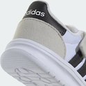 Detail van de hiel van een witte kindersneaker met een suède overlay, zwart detail met Adidas-logo en witte zool.