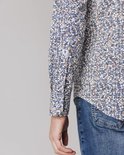 Close-up mouw van een man met blauw-wit met bruine print overhemd.